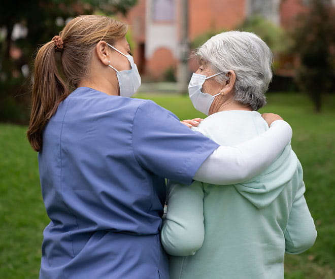 A hospital staff member offers emotional support to an elderly patient.