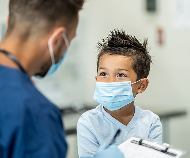 Pediatric physician interacting with young patient in examination room.