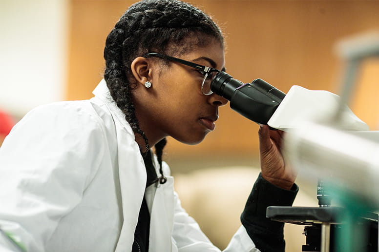 Leading health care change - Woman looking through microscope