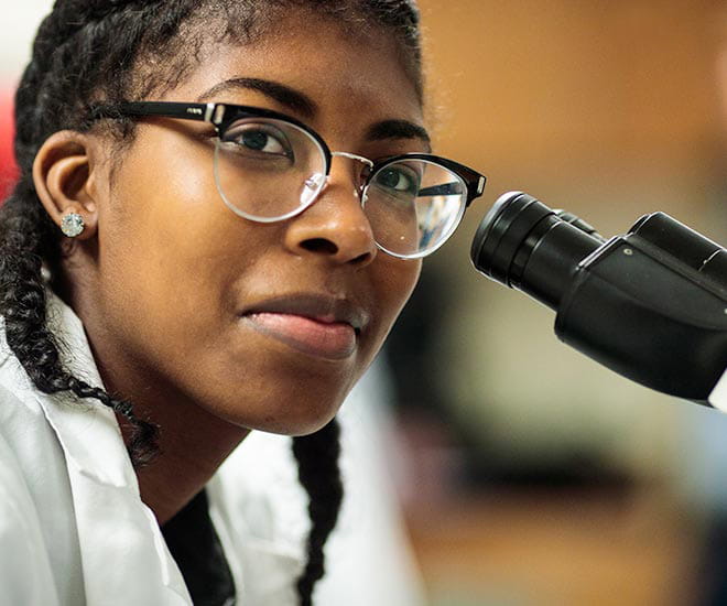 Young female medical student preparing to view slide in microscope.